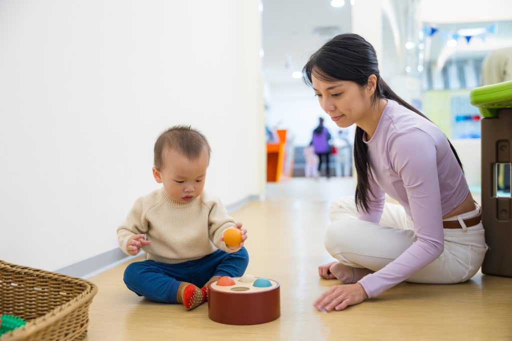 Woman Watching Baby Play with Toys Indoors